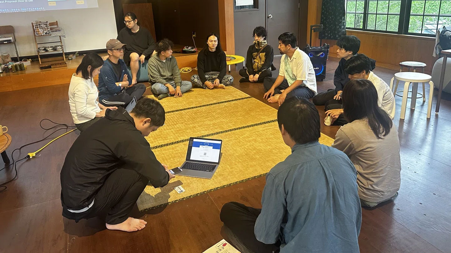 12人の大人が輪になって座り話し合っている様子