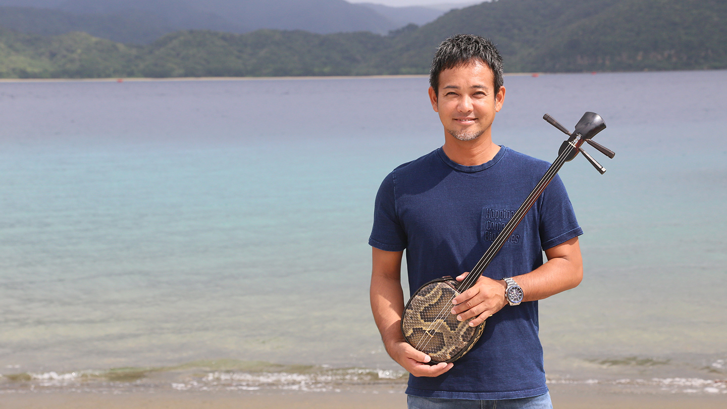 きれいな海の波打ち際で三振をもって微笑む池田卓さん