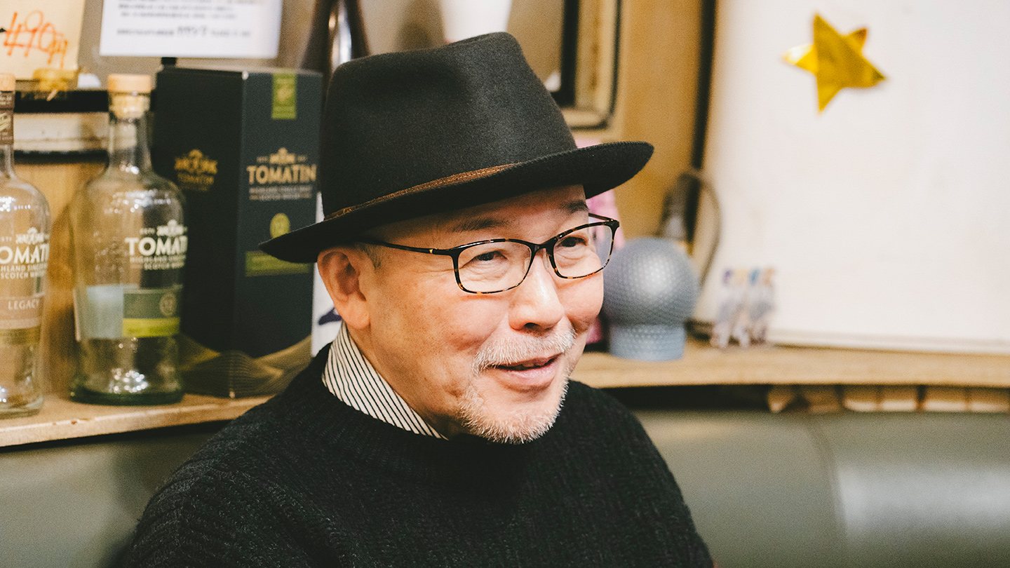 喫茶店の店内で、帽子と眼鏡を身につけ穏やかに話す久住昌之さん