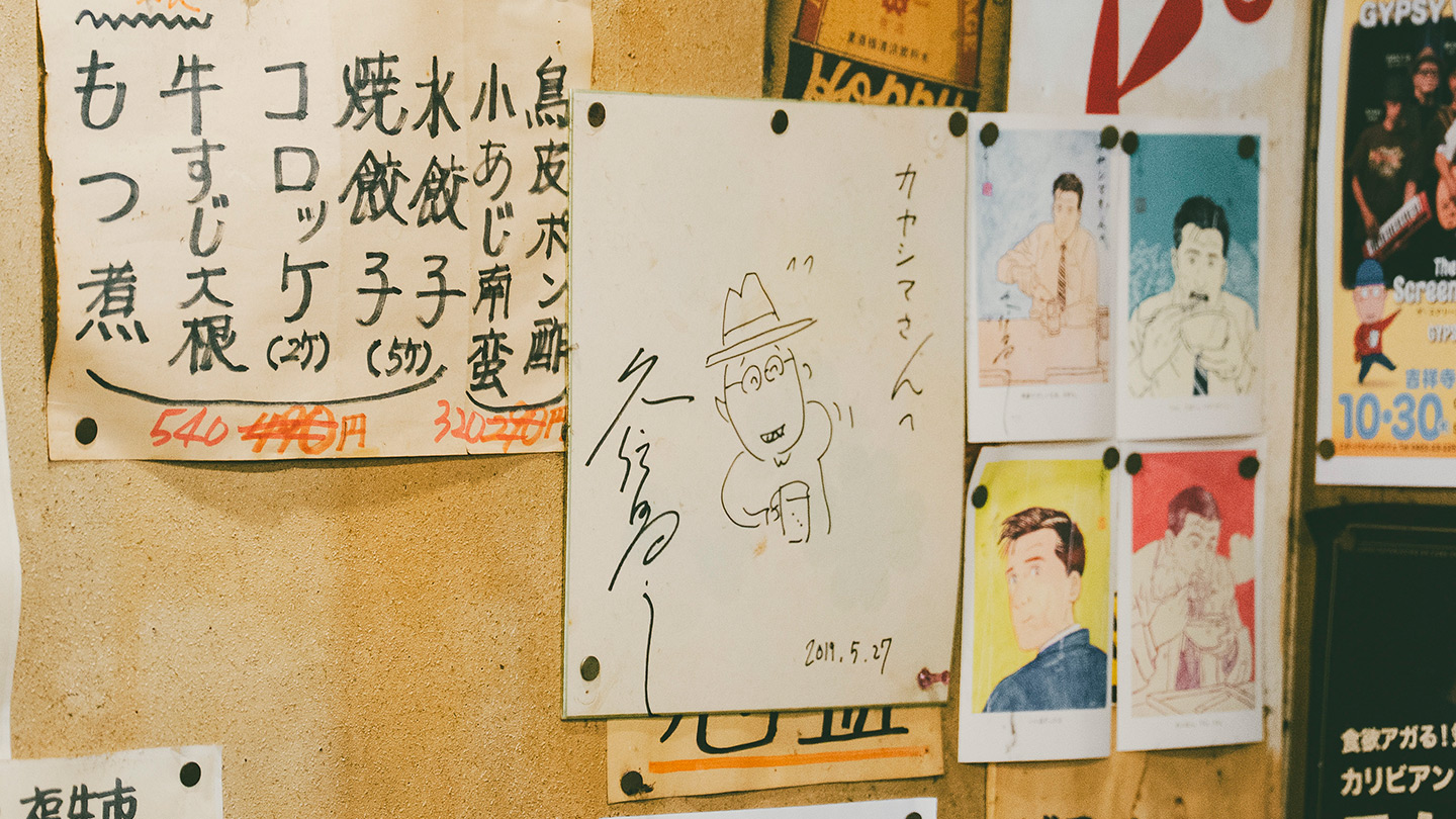 店内の壁に貼られた手書きメニューと、久住昌之さんのサイン色紙。『孤独のグルメ』のイラストも並ぶ