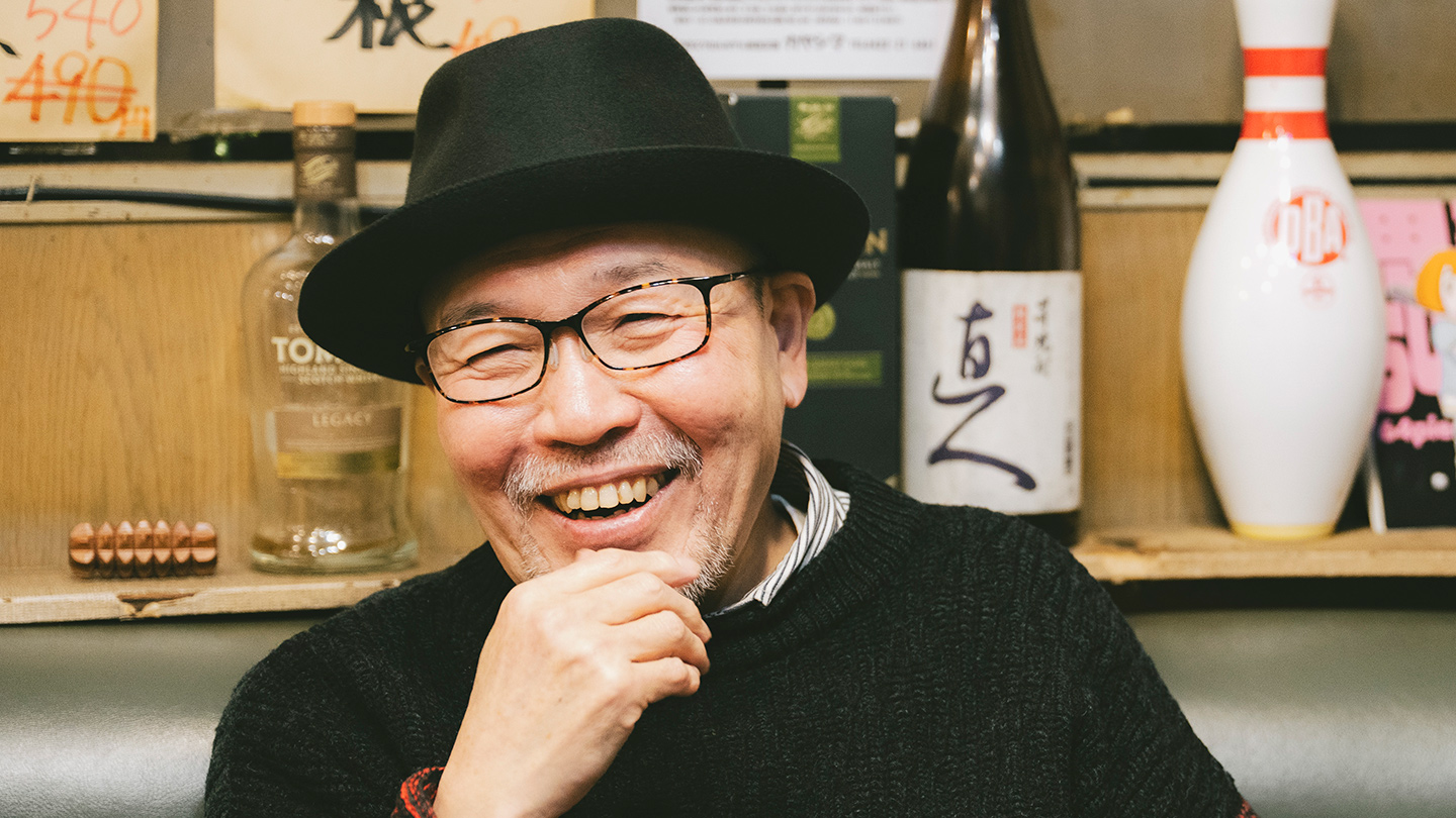 喫茶店のソファ席で笑顔を見せながらインタビューを受ける久住さん