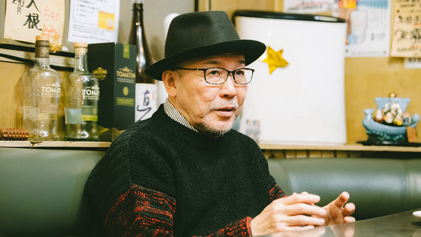 喫茶店のソファ席で身振りを交えながら話す久住昌之さん