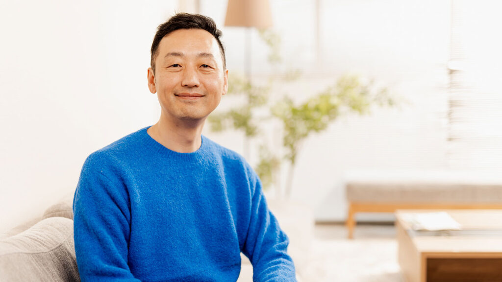 関治之さんがソファに座って正面を向いているポートレート