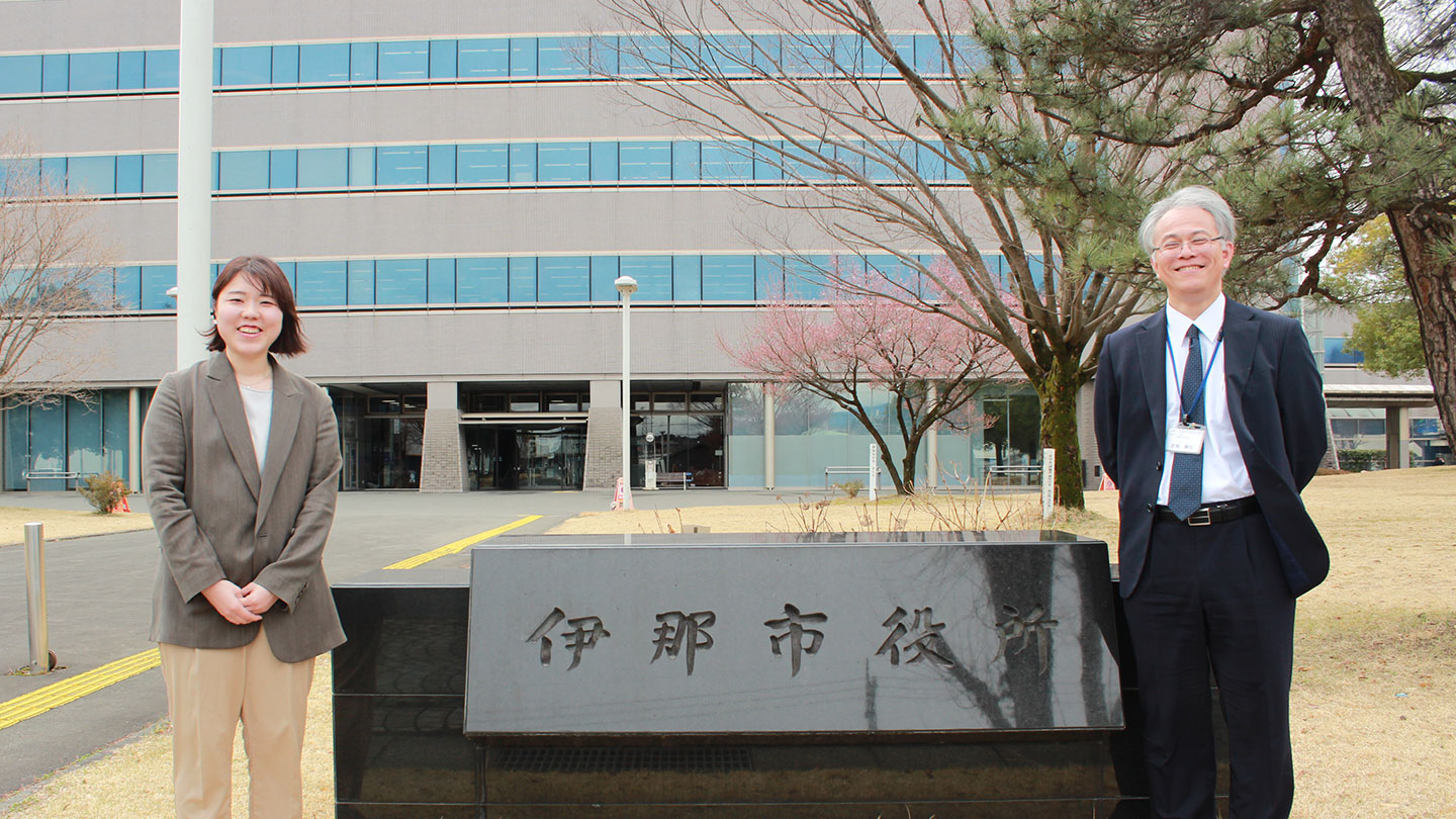 伊那市役所の看板前に並ぶ宮島さんと石倉さん