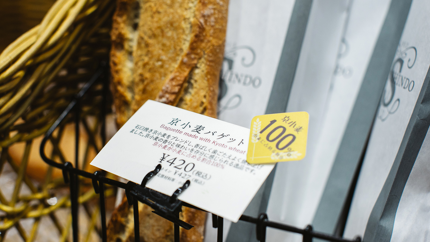 かごに入ったバゲットと「京小麦バゲット」と書かれた値札