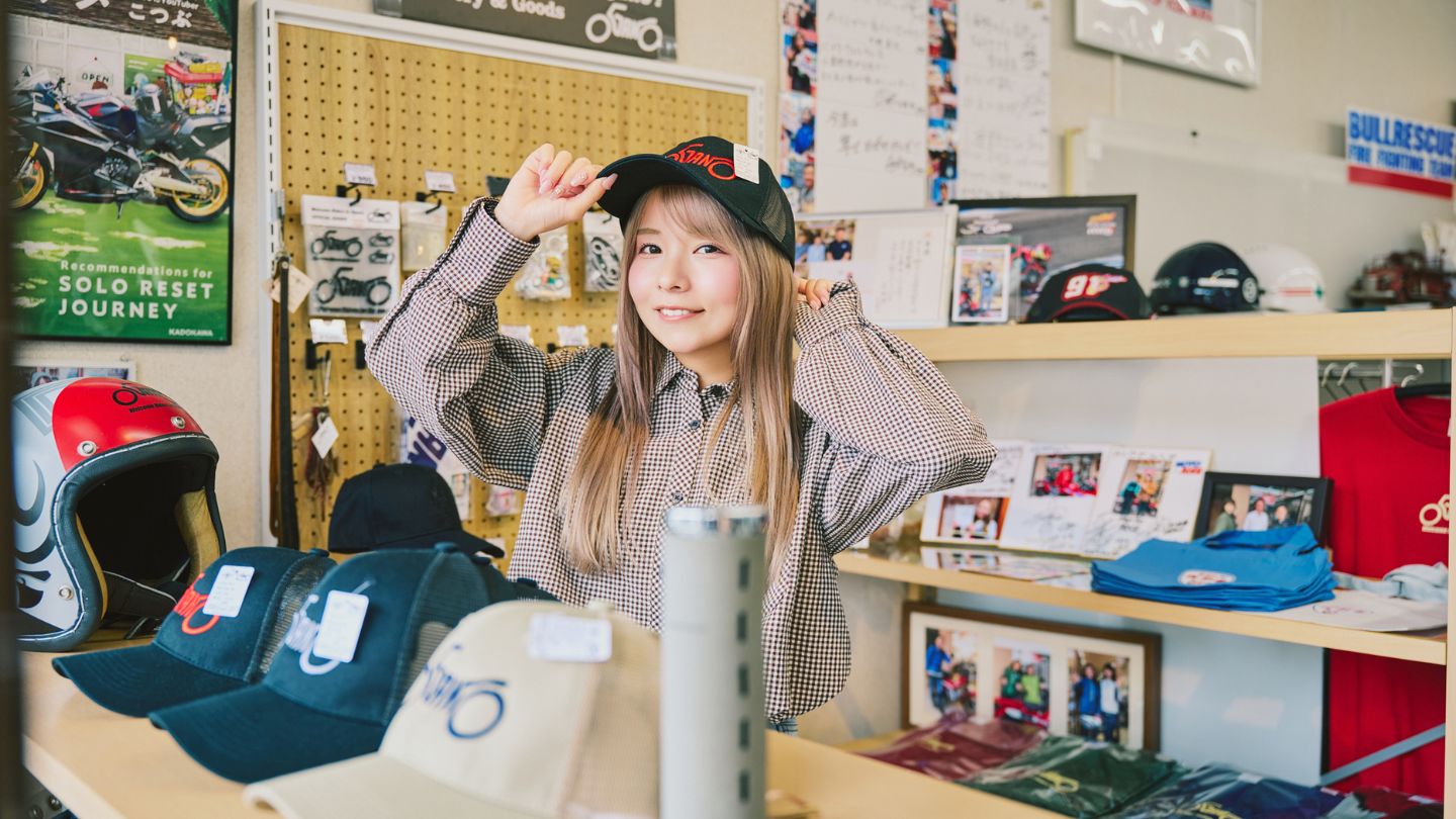 店内のグッズ売り場でバイクの刺繍が入ったキャップをかぶるこつぶさん