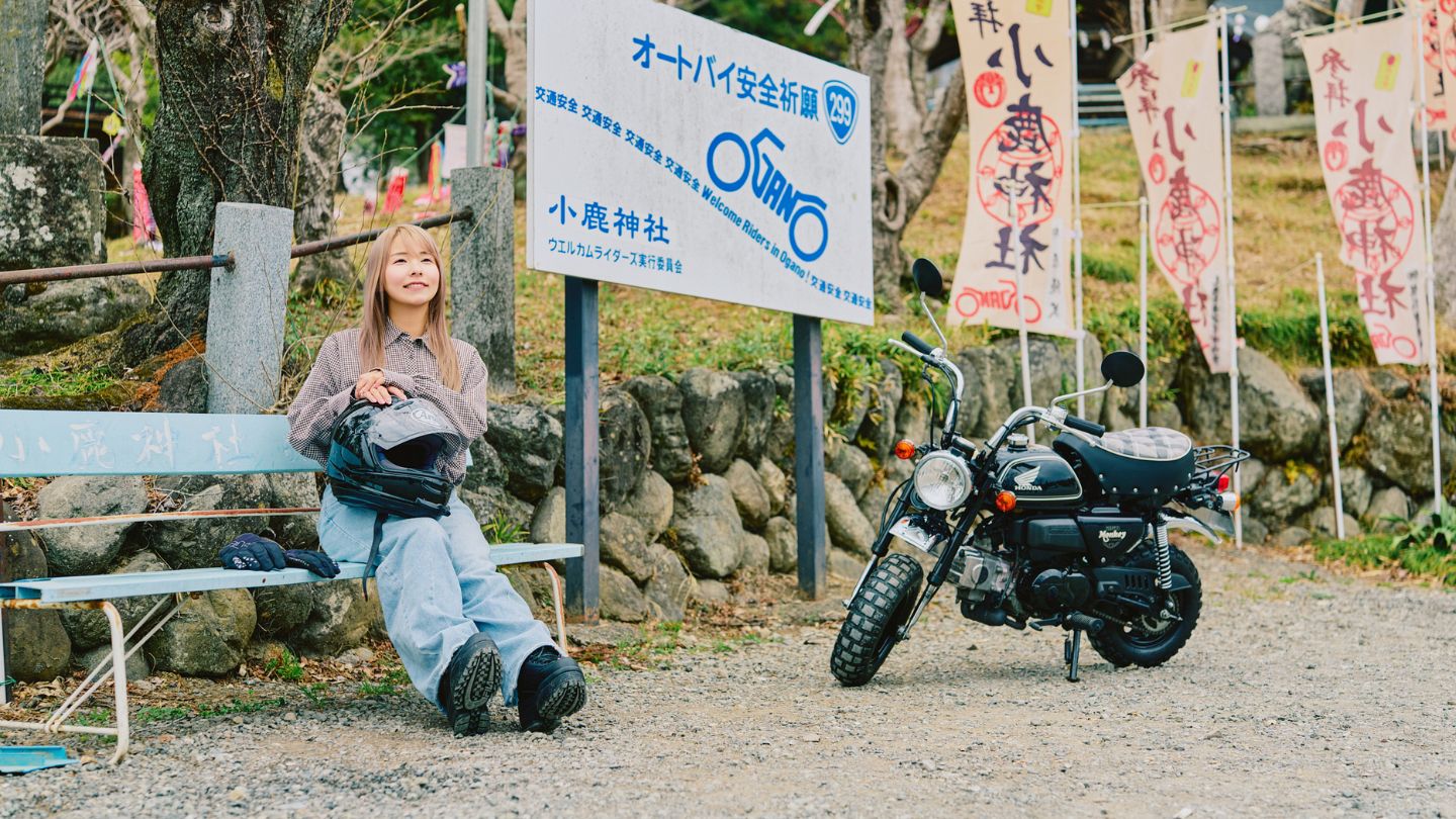 小鹿神社のベンチに座るこつぶさん。横には愛車のモンキーがある