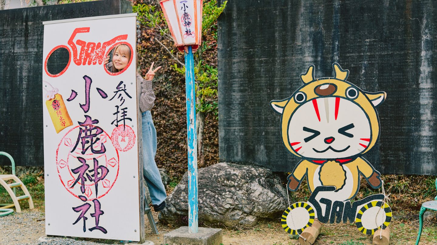 小鹿神社の顔出しパネルから顔をのぞかせ、笑顔を見せるこつぶさん