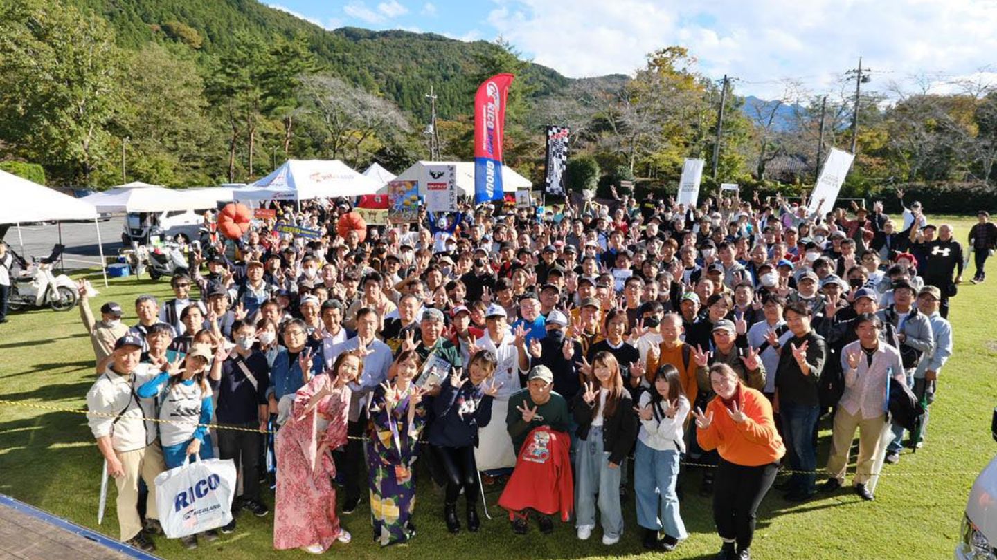 大勢のイベント来場者が晴天の下笑っている集合写真