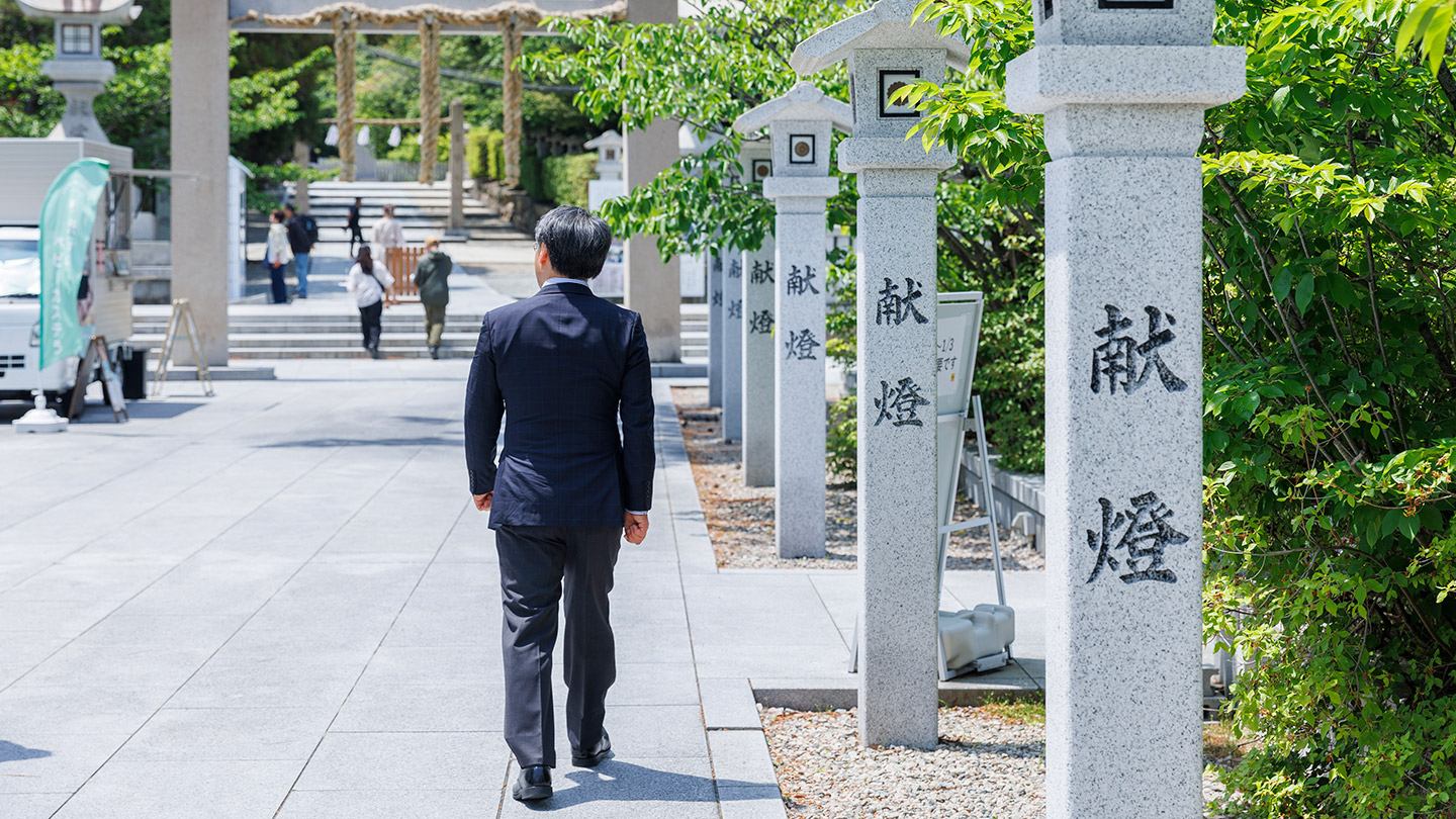 石灯籠が並ぶ廣田神社の参道を歩く島村さん