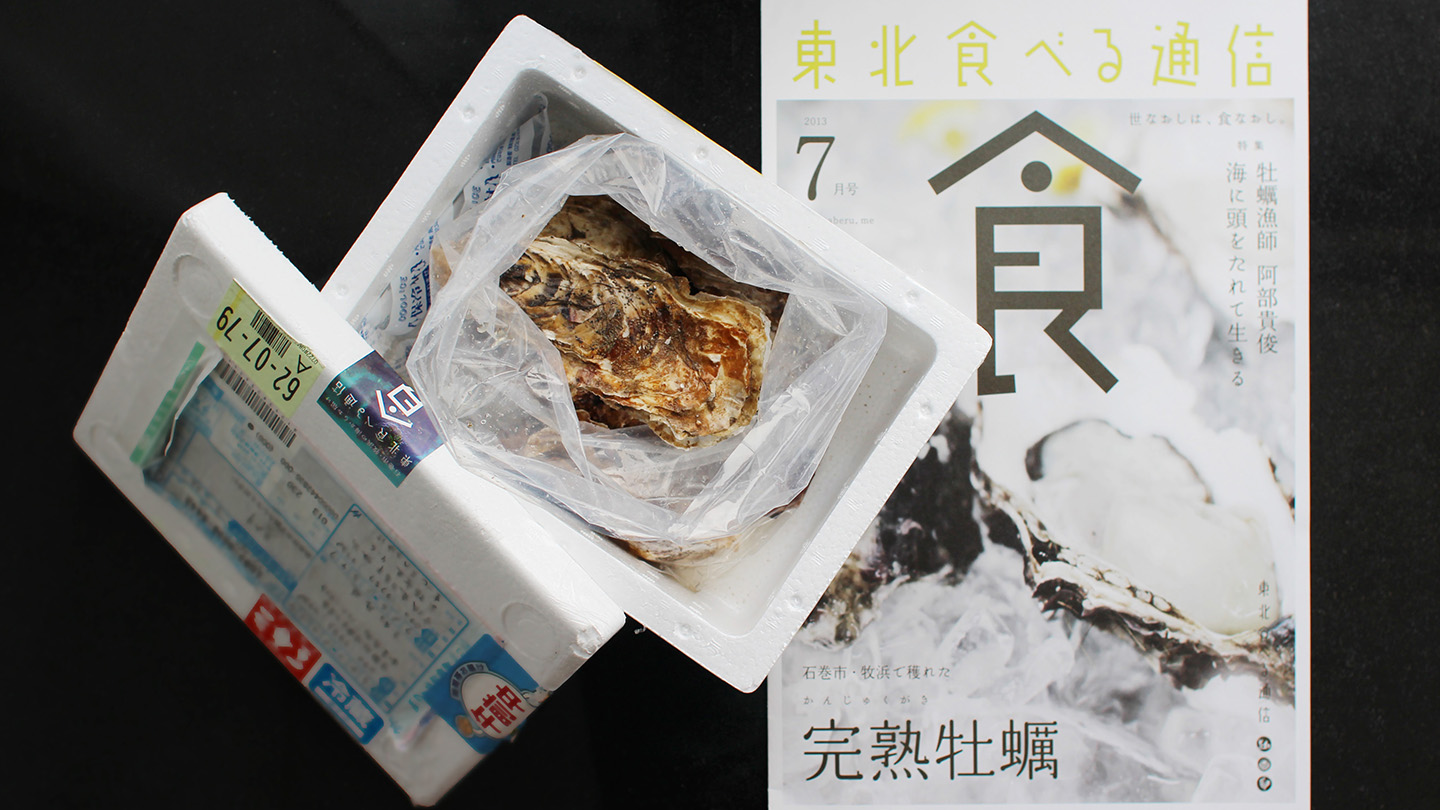 発泡スチロールの箱に入った牡蠣と、完熟牡蠣を特集した冊子が並んでいる