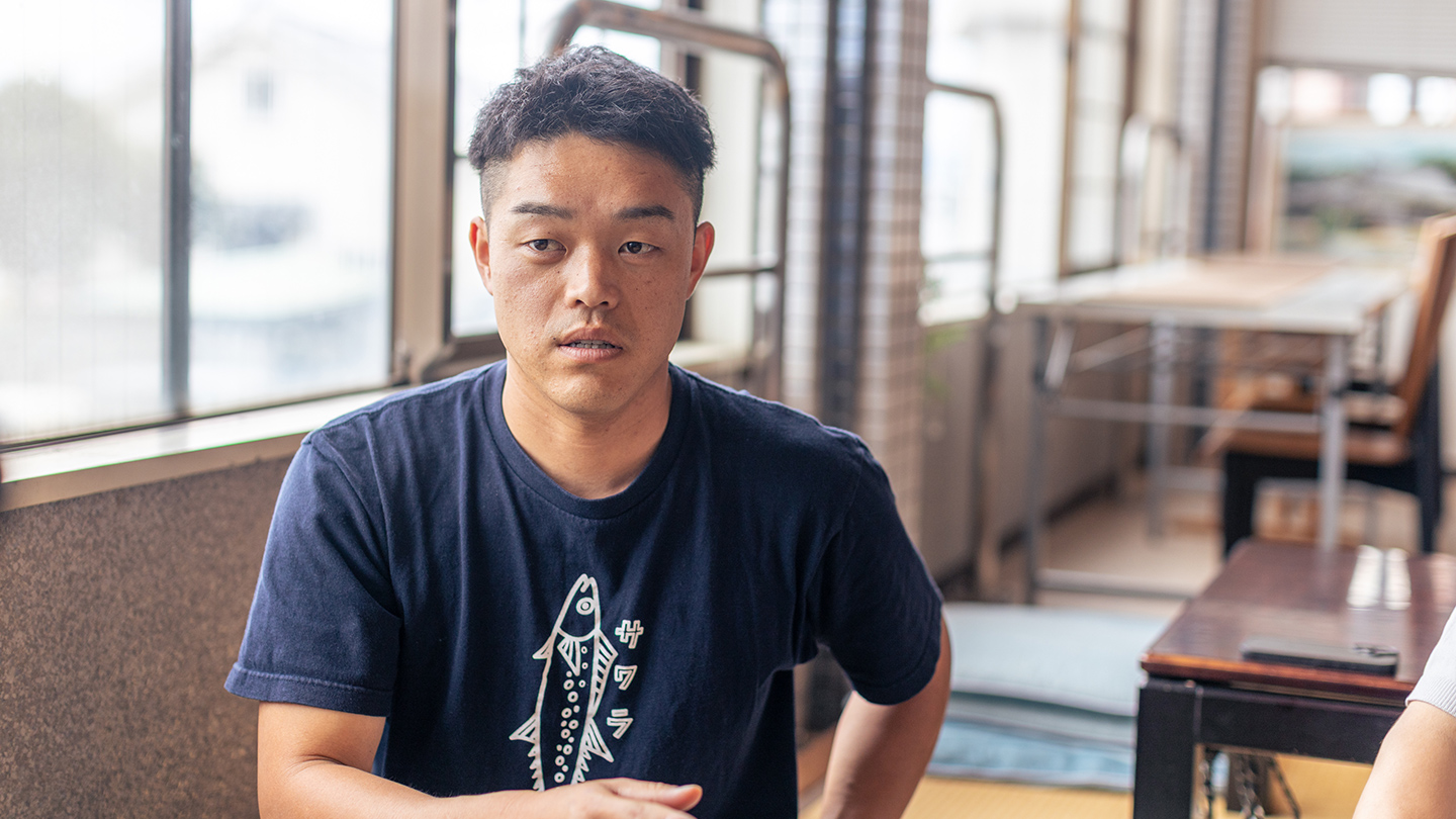 屋内で窓辺に座って話をしている大石一仁さん