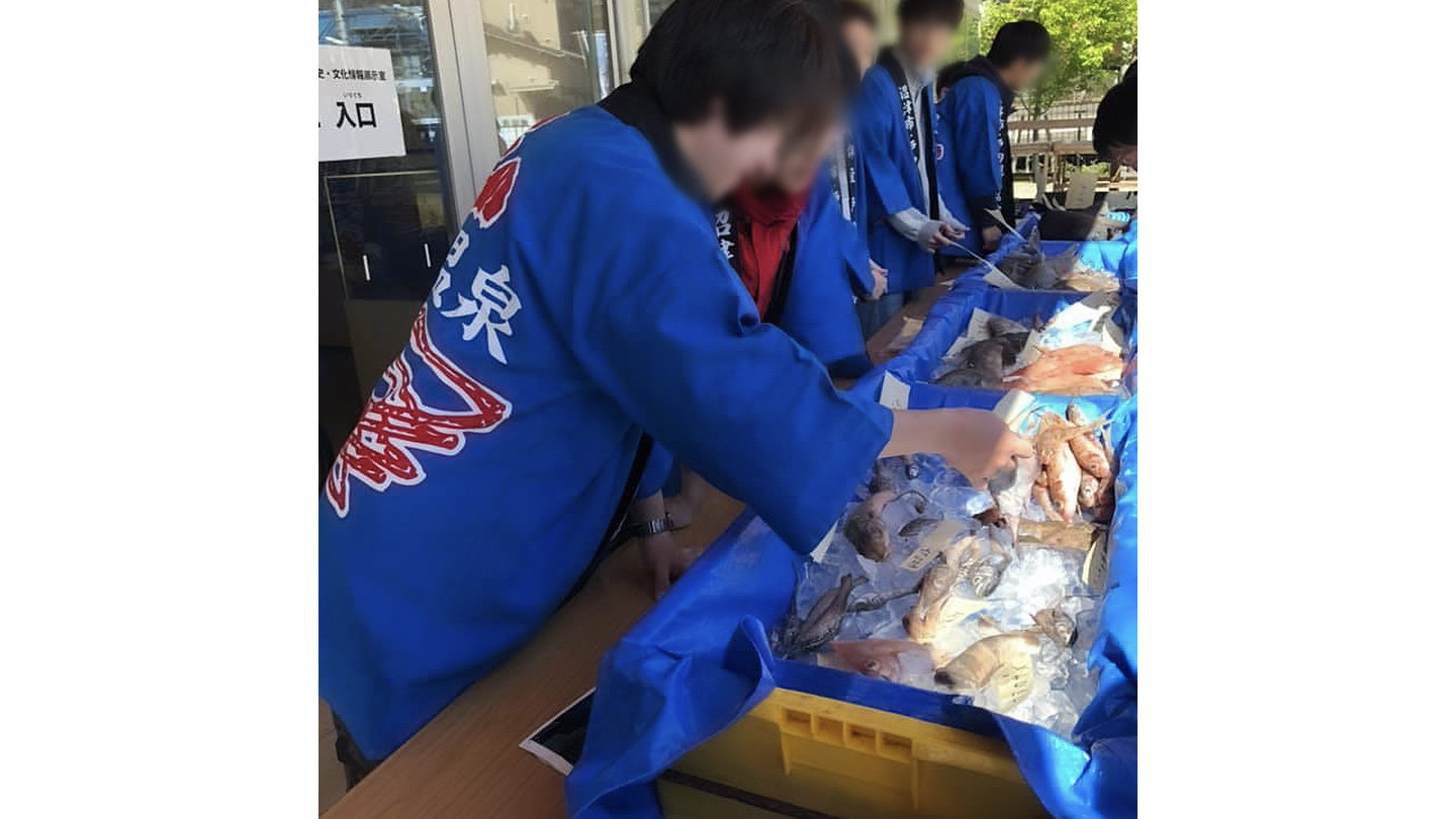 青いハッピを着て魚を展示する人々
