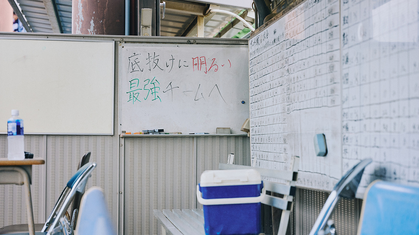 野球部のベンチにあるホワイトボードに「底抜けに明るい最強チームへ」というスローガンが書かれている
