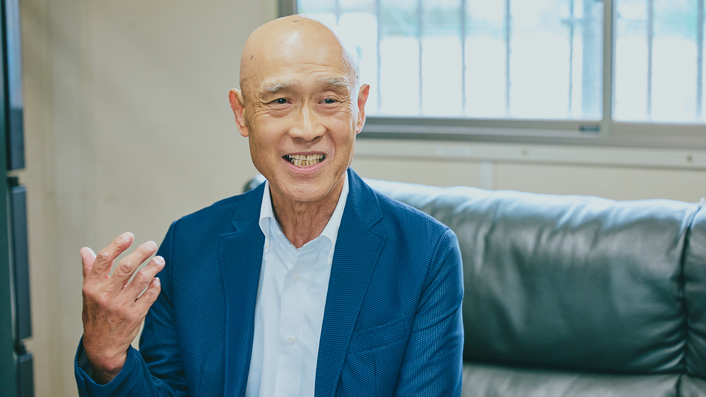 いジャケット姿でインタビューに答える坂口清貴さん