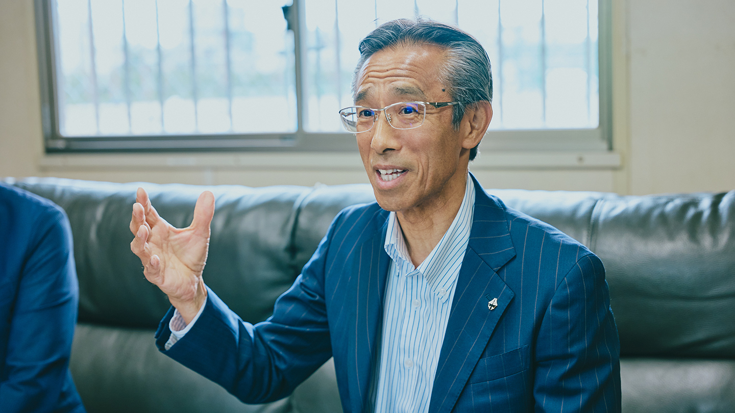 スーツ姿でインタビューに答える石榑淳さん