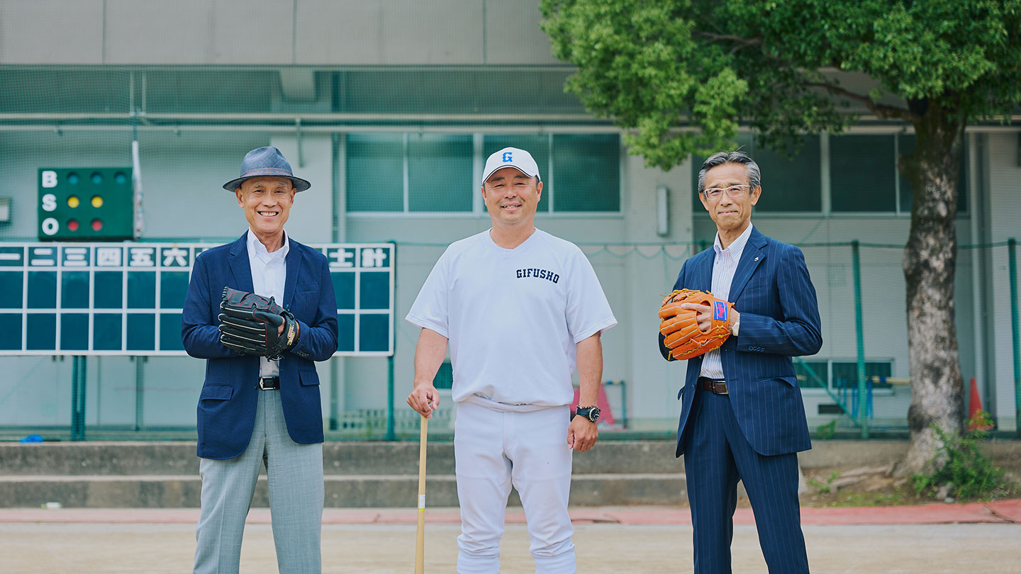 野球のグラウンドにグローブやバットを手にした坂口清貴さん、藤井潤作監督、石榑淳さんが立っている
