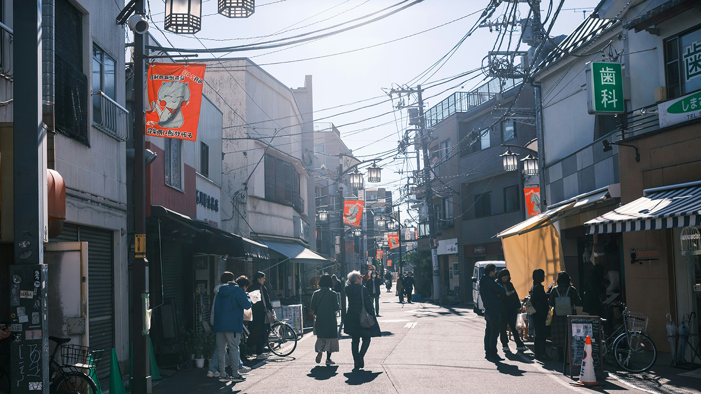 商店街の通りを歩く人々と、沿道に並ぶ店舗
