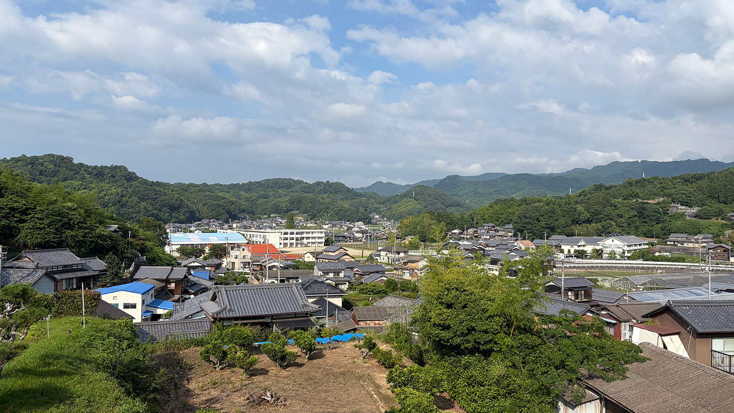 山に囲まれた地区に、住宅や畑が広がっている