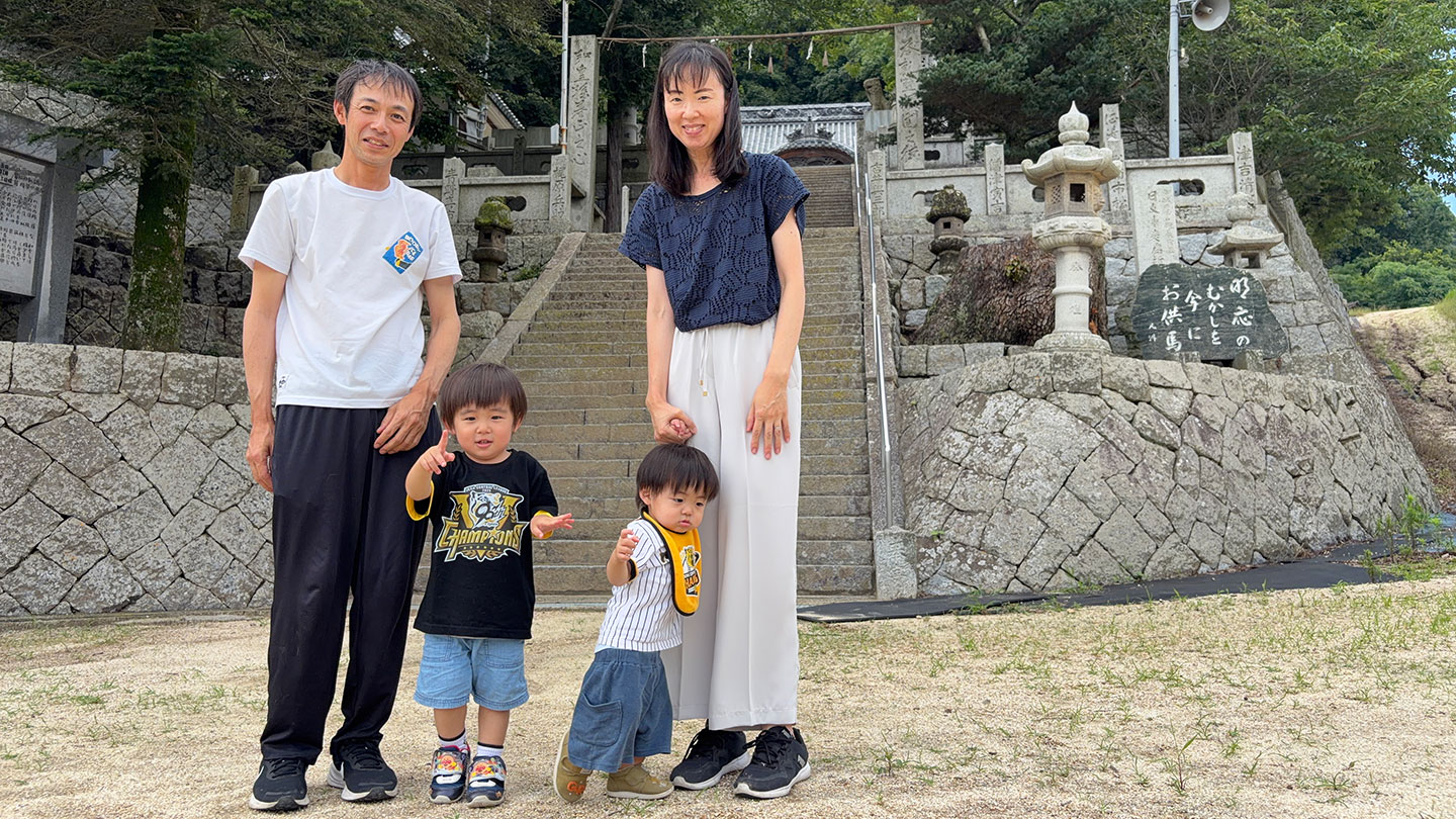 社の前で、村上さんと家族が並んで立っている