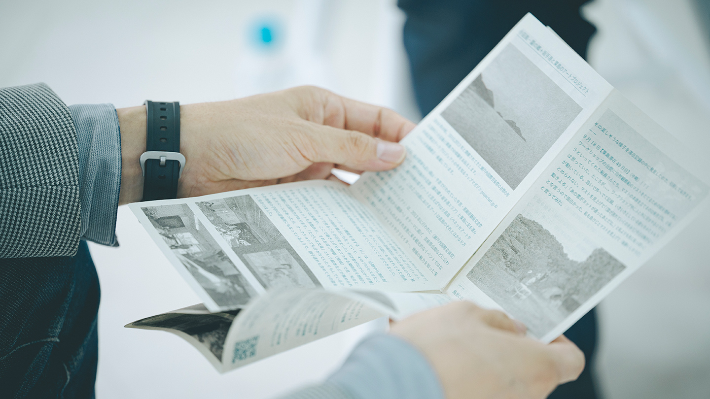 橋本さんが制作したZINEを開いて読む仲俣さん