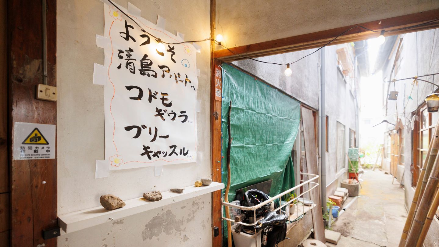「ようこそ清島アパートへ」と書かれた模造紙が飾ってある土間
