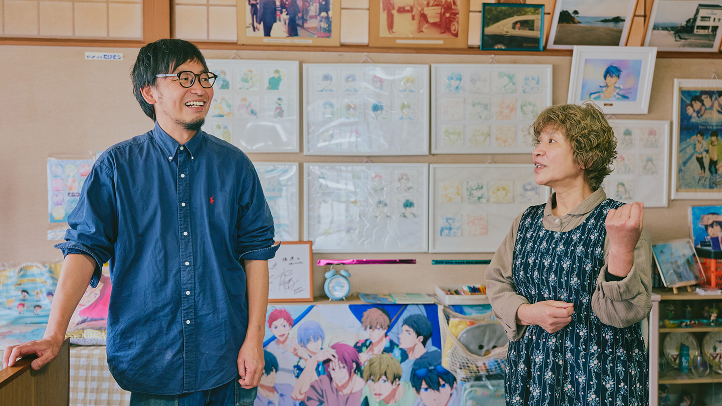 『Free!』グッズの棚を背景に話をする田中さんとたけそうの女将・恵さん