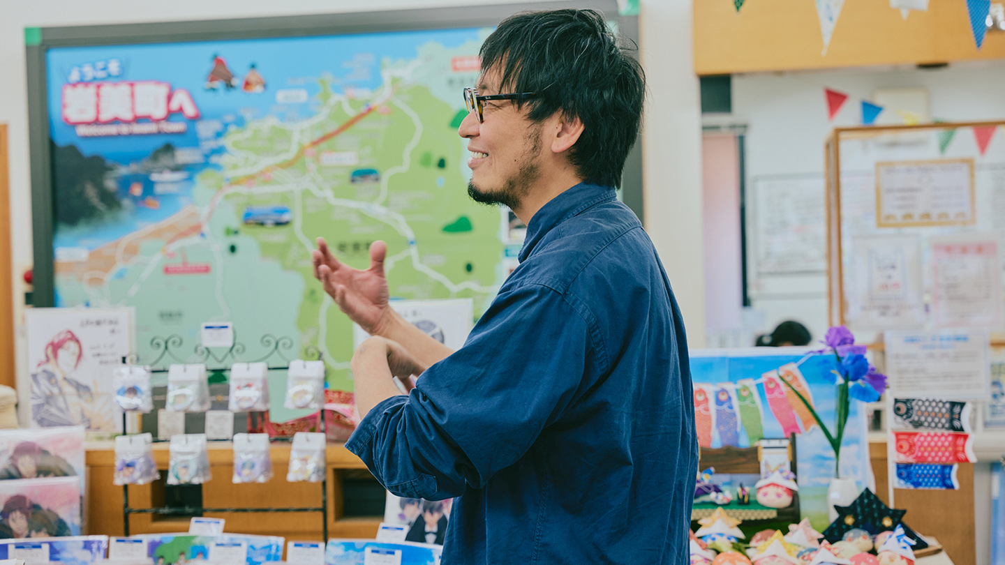 岩美町観光協会のロビーで手振りを使って話す田中さん