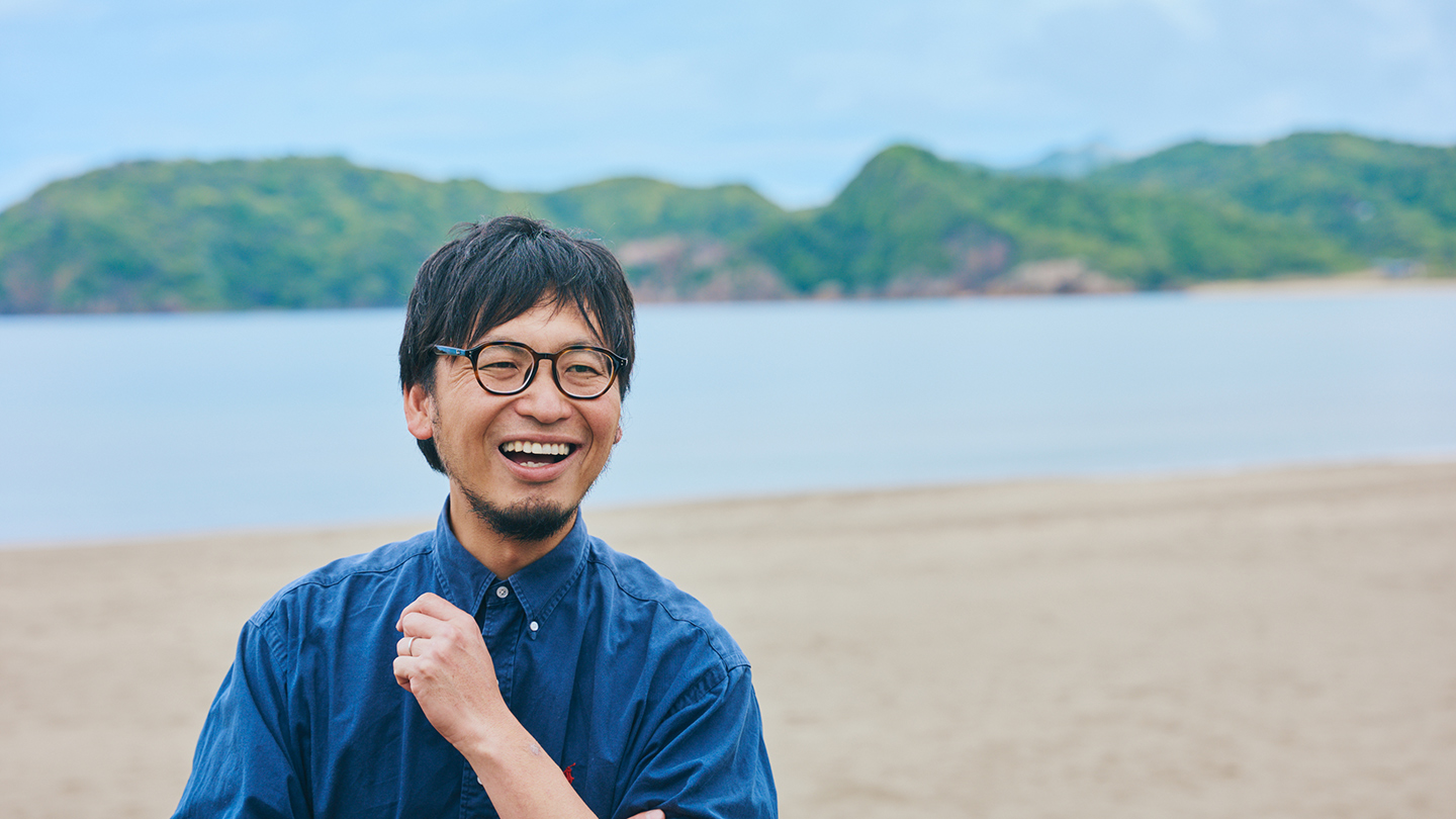 岩美の海を背景に笑う田中さん