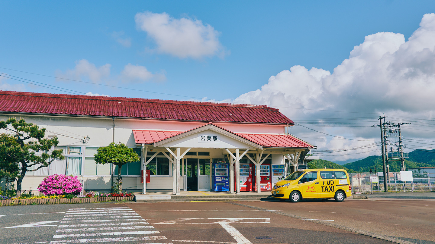 青空の下に赤い屋根の岩美駅がある風景