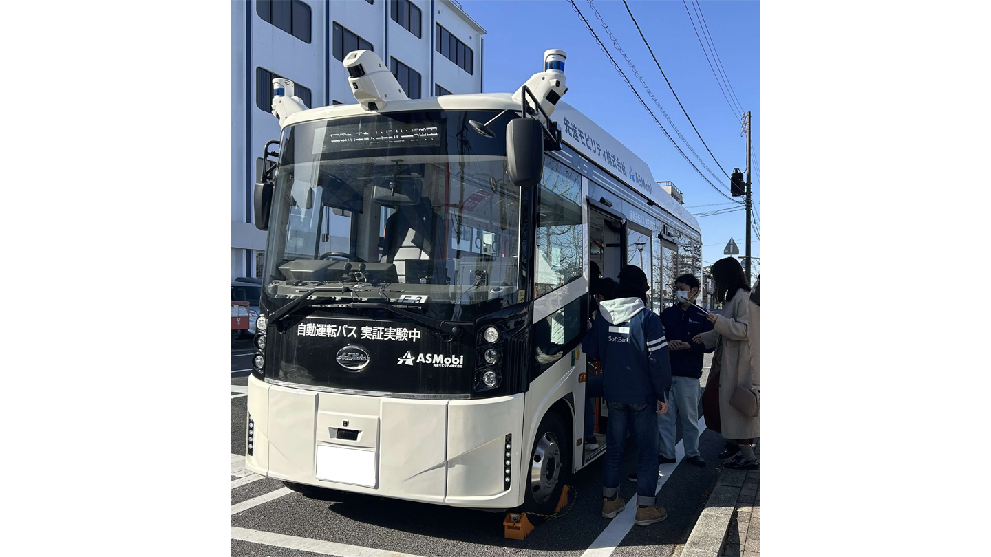 「自動運転バス実証実験中」と書かれた白黒のバスに人が乗り込む