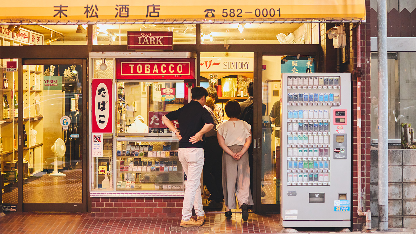 「末松酒店」と書かれた酒屋に入る角文研一行